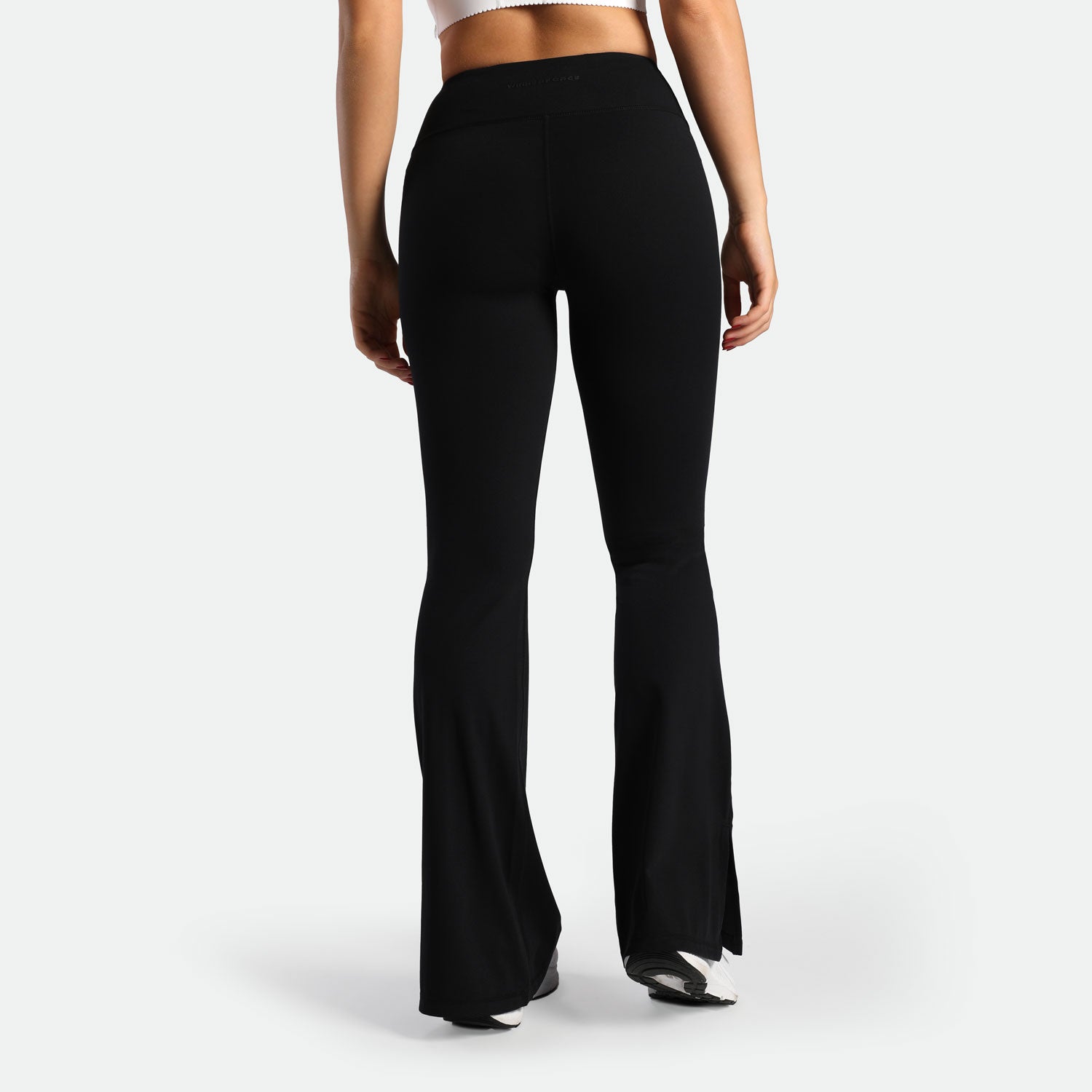 a back view for fit woman wearing flared legging black with shoes white 