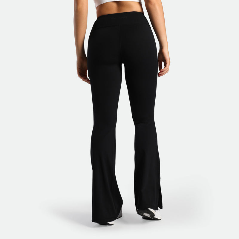 a back view for fit woman wearing flared legging black with shoes white 