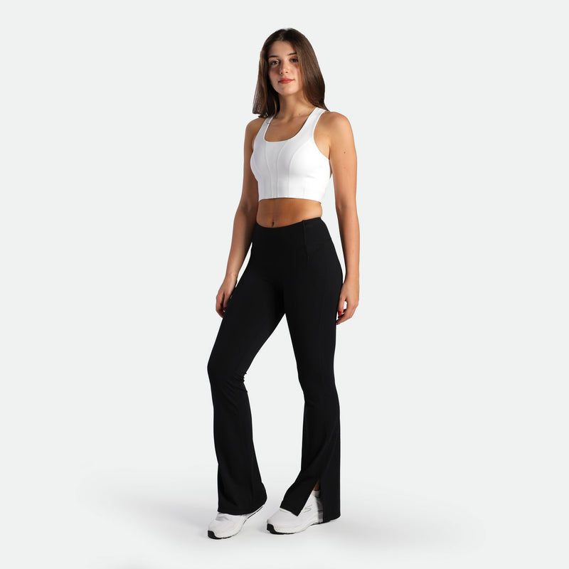 a fit woman wearing crop top white and flared legging black plus the shoes white 