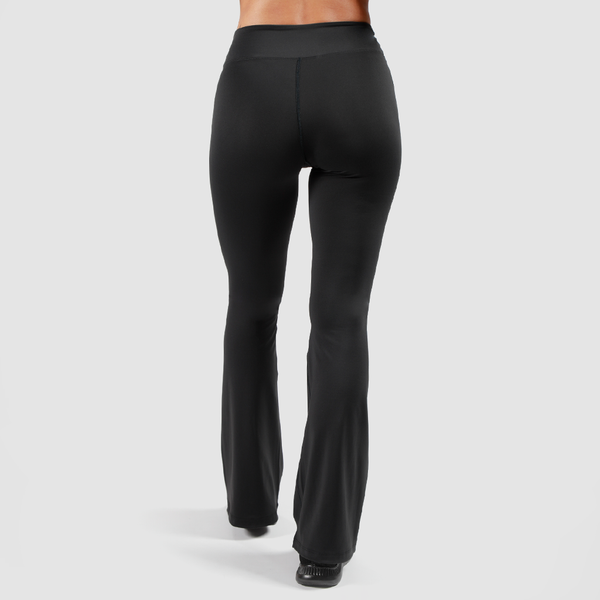 a back view for woman  wearing flared legging with shoes black ,the background is light grey