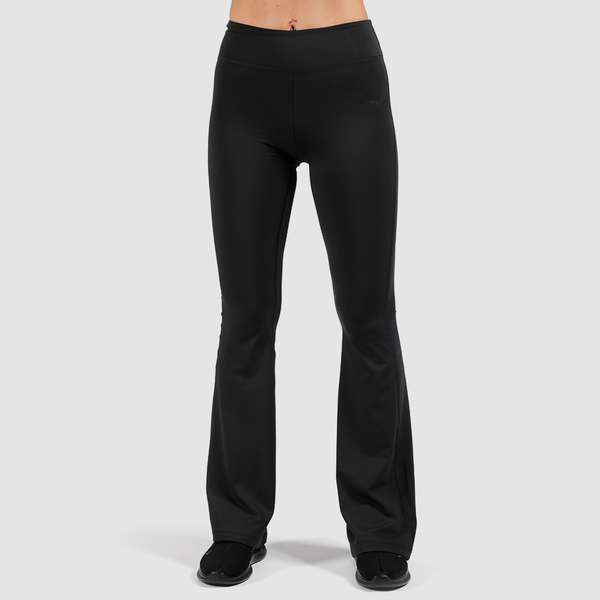 a fit woman wearing flared legging and shoes black ,plus the background s light grey 