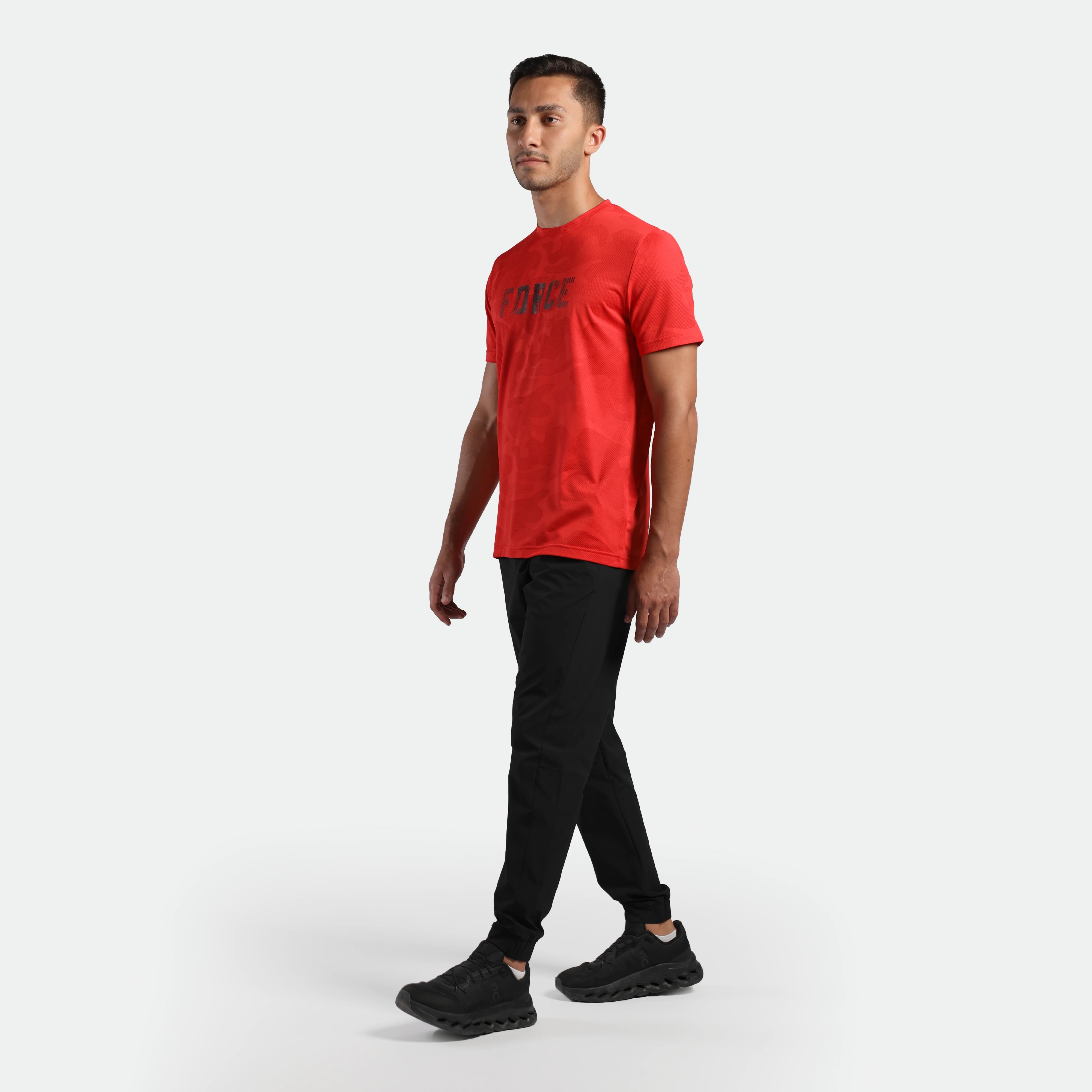 Man wearing a red t-shirt and black pants ,plus the shoes 