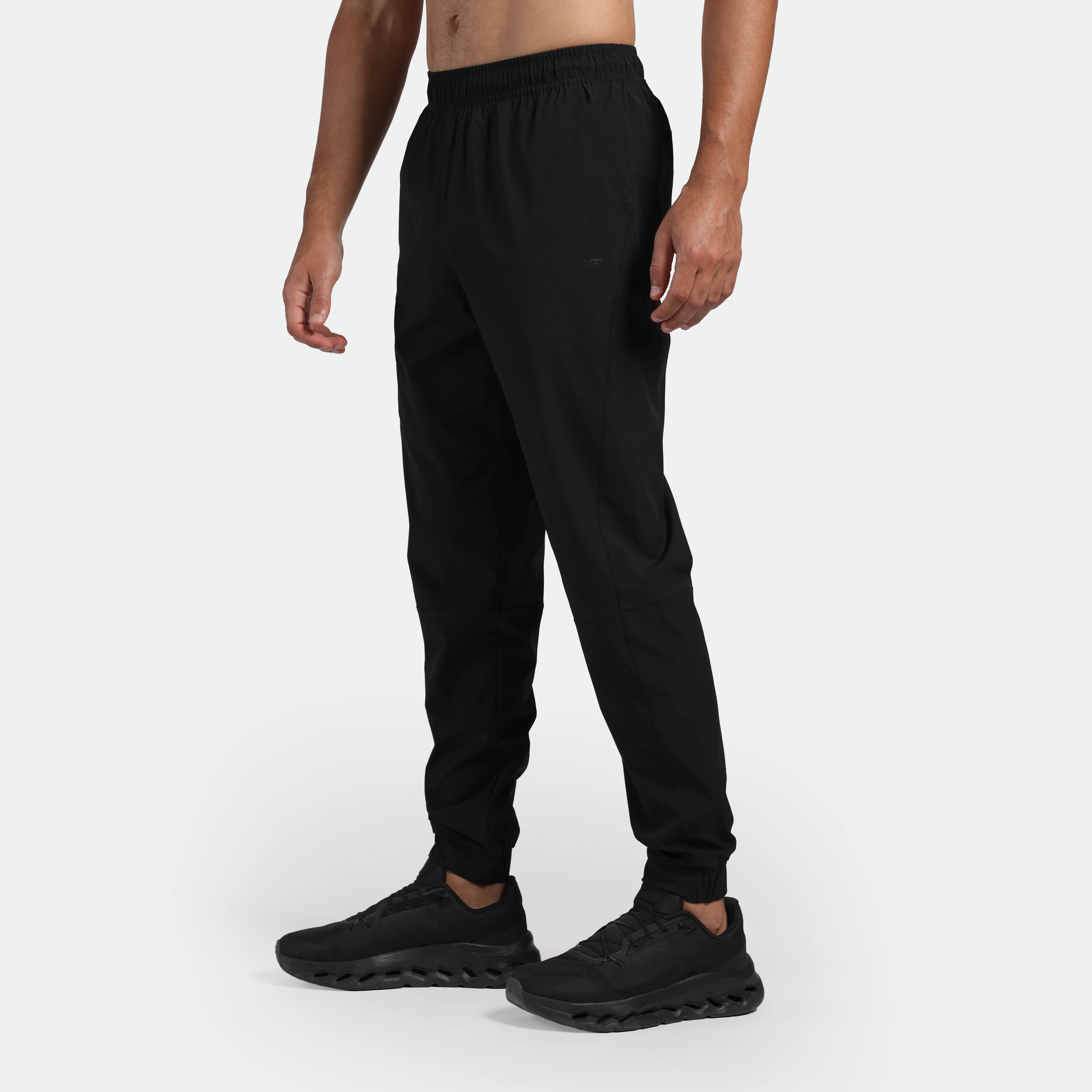 a fit man stand at right and wearing pants black with shoes  black 
