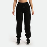 a woman wearing jogger pant with tow pocket and shoes same color is black ,plus the background is light grey 