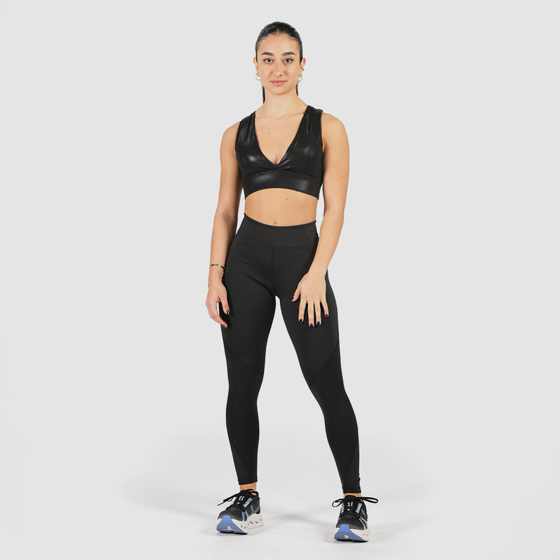 a fit woman stand with pose and look at the camera ,she wearing matching bra and legging ,shoes mix color, plus the background is light grey 
