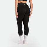 Person wearing black leggings and white socks on a light gray background