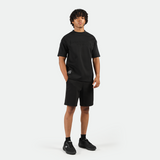 a fit man wearing matching set black ,t-shirt black with short ,plus the shoes black 