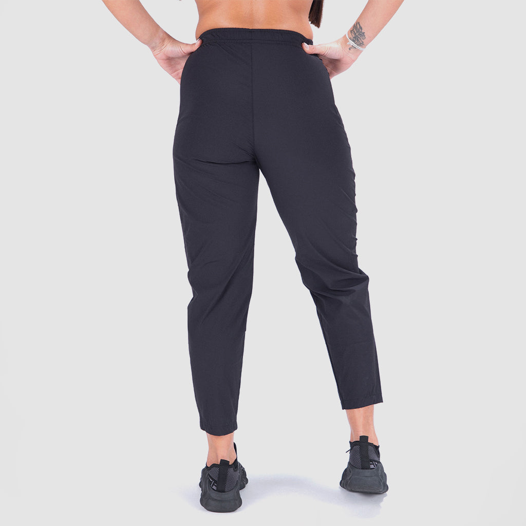 a back view for fit woman wearing pant black and  black shoes alethic ,plus the background is light grey 