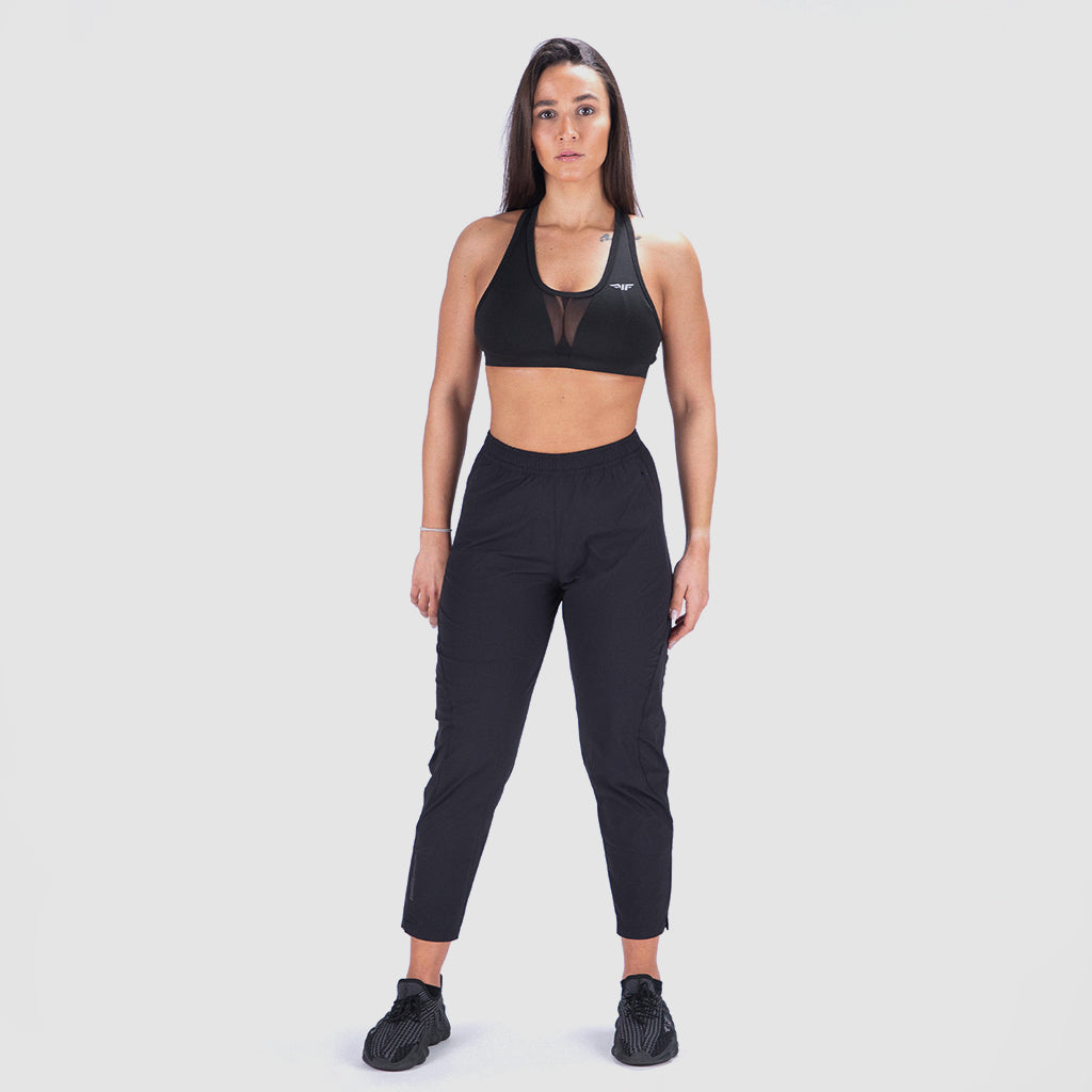 a fit woman look at camera and wearing matching bra and legging with black shoes athletic ,plus the background is light grey 