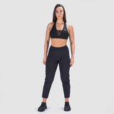 a fit woman look at camera and wearing matching bra and legging with black shoes athletic ,plus the background is light grey 