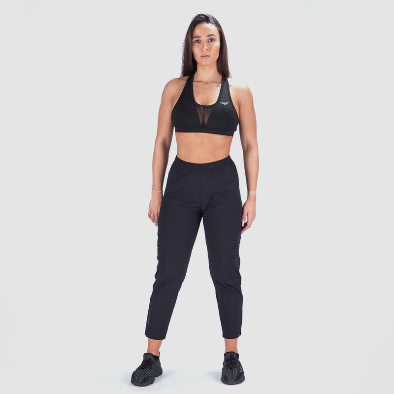 a fit woman look at camera and wearing matching bra and legging with black shoes athletic ,plus the background is light grey 