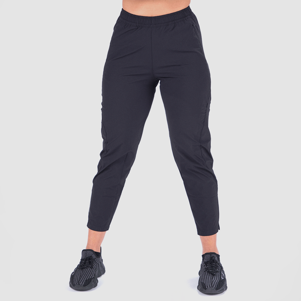 a fit woman wearing pant black with shoes  black ,plus the background is light grey 