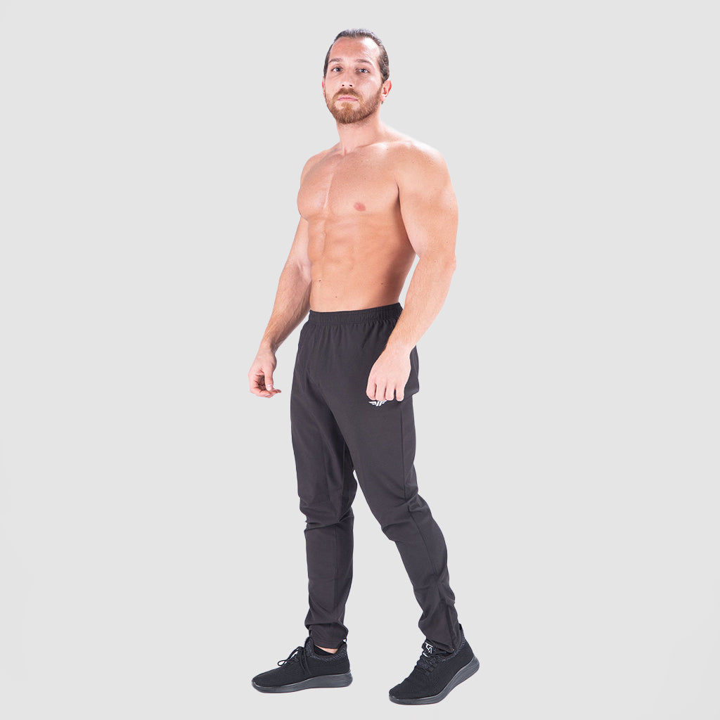 a fit man wearing  just pants  black with logo pus shoes black 