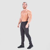 a fit man wearing  just pants  black with logo pus shoes black 