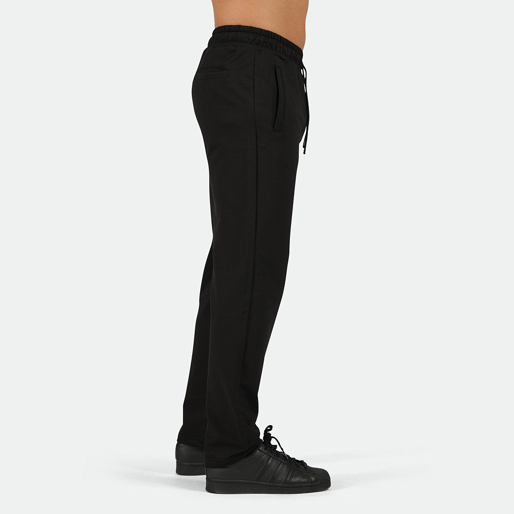 a fit man stand at right  and wearing pants black with shoes  black 