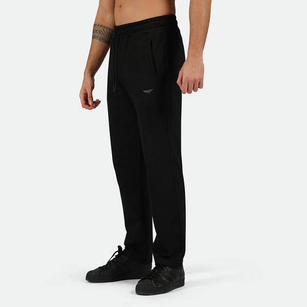 a fit man stand at right  and wearing  pants black with logo ,plus shoes black 