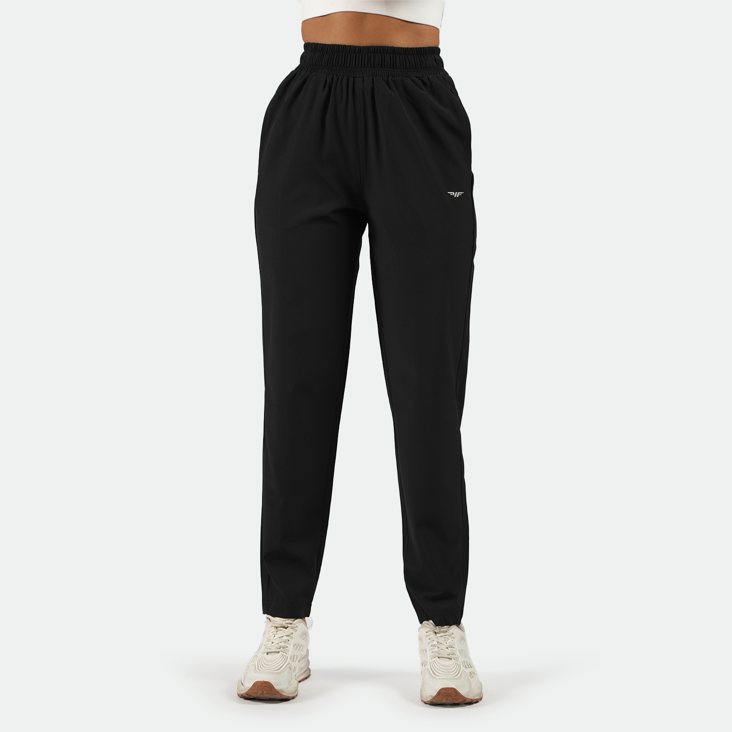 a fit woman wearing black  pants with shoes white ,plus the background is light grey 