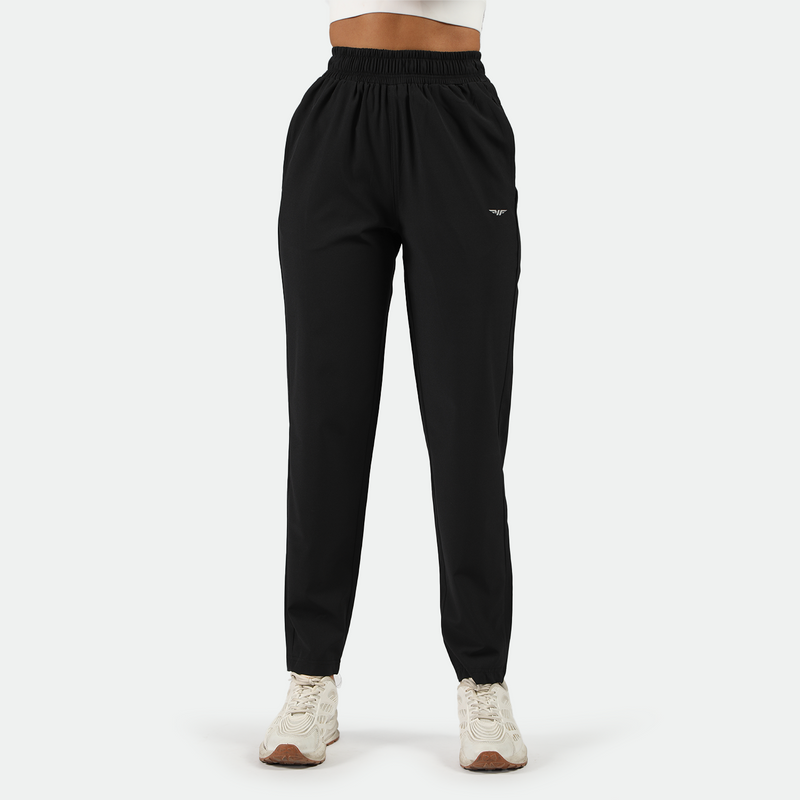 a fit woman wearing black  pants with shoes white ,plus the background is light grey 