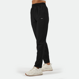 a fit woman stand at right and wearing 
 black pants with shoes white ,plus the back round is light grey 