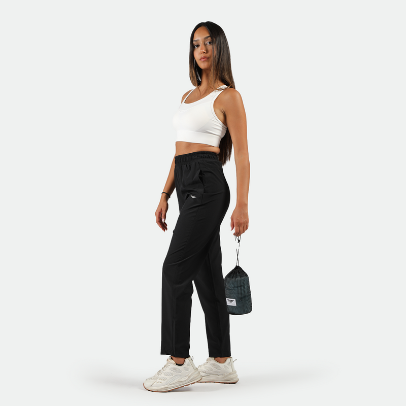 a fit woman wearing white sports bra with black pants and  shoes ,plus the background is light grey 