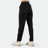 a back view for fit woman wearing black pants with  shoes white ,plus the background is light grey 