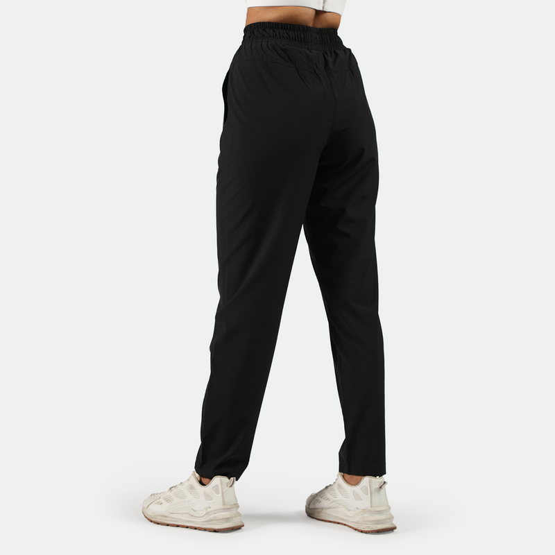 a back view for fit woman wearing black pants with  shoes white ,plus the background is light grey 