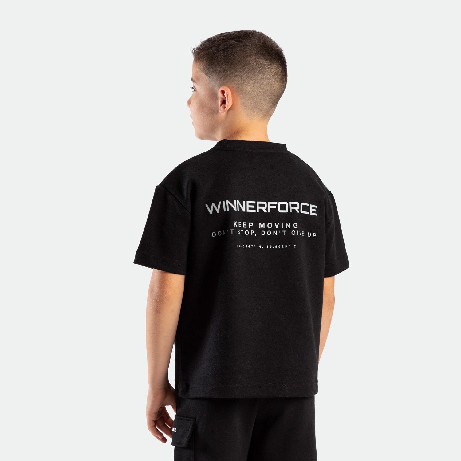 a back view for young boy wearing matching set black with logo and short  black with tow pocket 