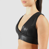 a woman wearing  faux leather  bra with background light grey