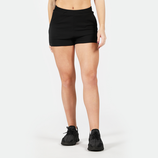 a fit woman wearing short black with shoes black ,plus the background is light grey 
