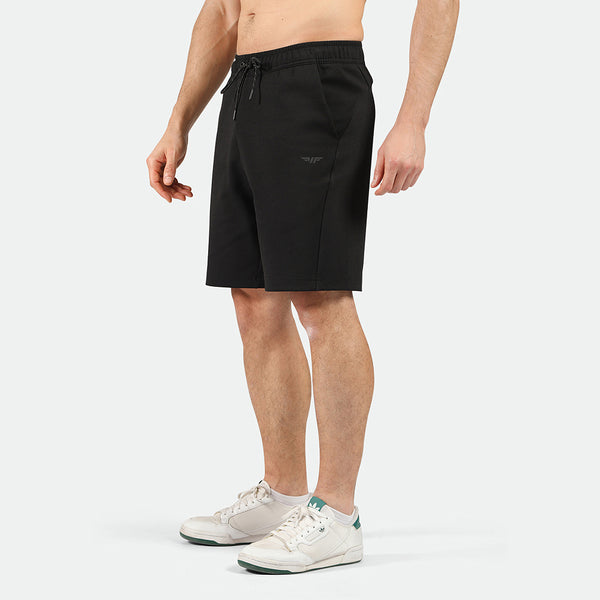 a fit man  stand at right and wearing short black with shoes 