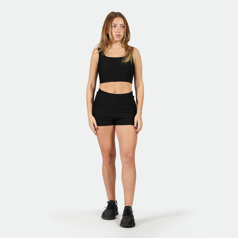 a fit woman wearing matching bra and 
 black short with shoes ,plus the background is light grey  