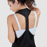 Woman in a black and white sports top with a racerback design seen from behind, hair tied up, conveying a modern and active vibe.