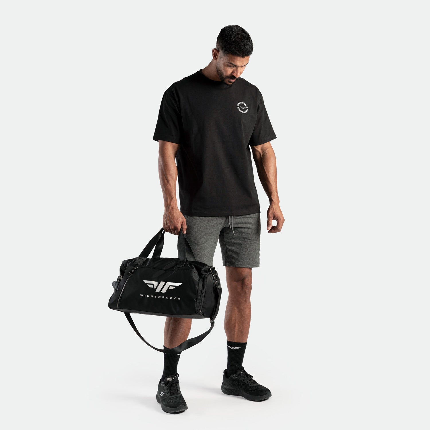 a fit man wearing t-shirt  black  with short grey ,plus the sock black and shoes and bag black 
