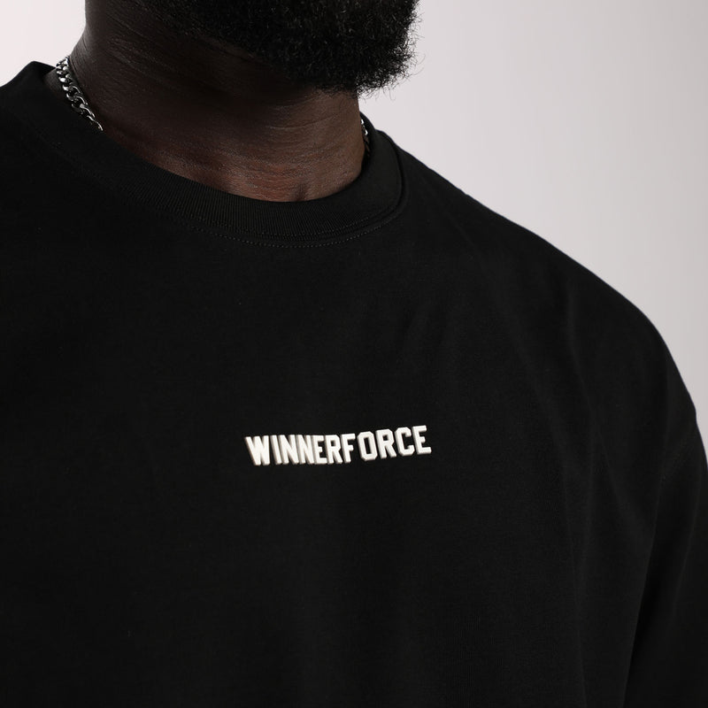 Close-up of a person wearing a black shirt with "WINNERFORCE" printed in white across the chest. The background is neutral, conveying a minimalist style.