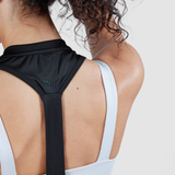 Close-up of a person with curly hair wearing a black and white sports bra, showing the back and shoulders. The image conveys a sporty and active vibe.