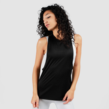 A woman with curly hair poses confidently in a sleeveless black top and white leggings against a plain background, conveying a sporty and stylish vibe.