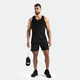 a fit man stand at right and wearing tank black with short black ,plus shoes 