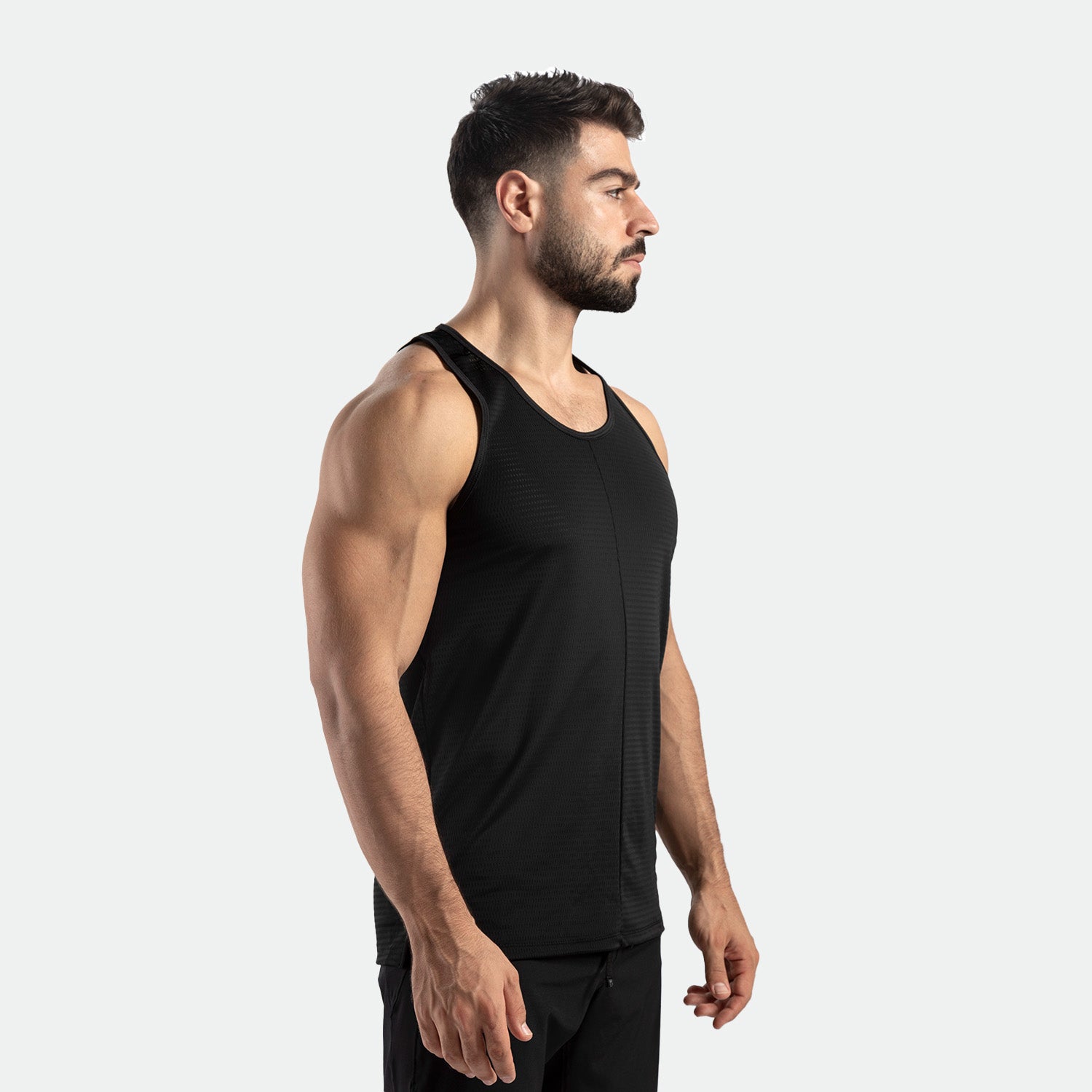 a fit man stand at right and wearing tank black  with pants black 