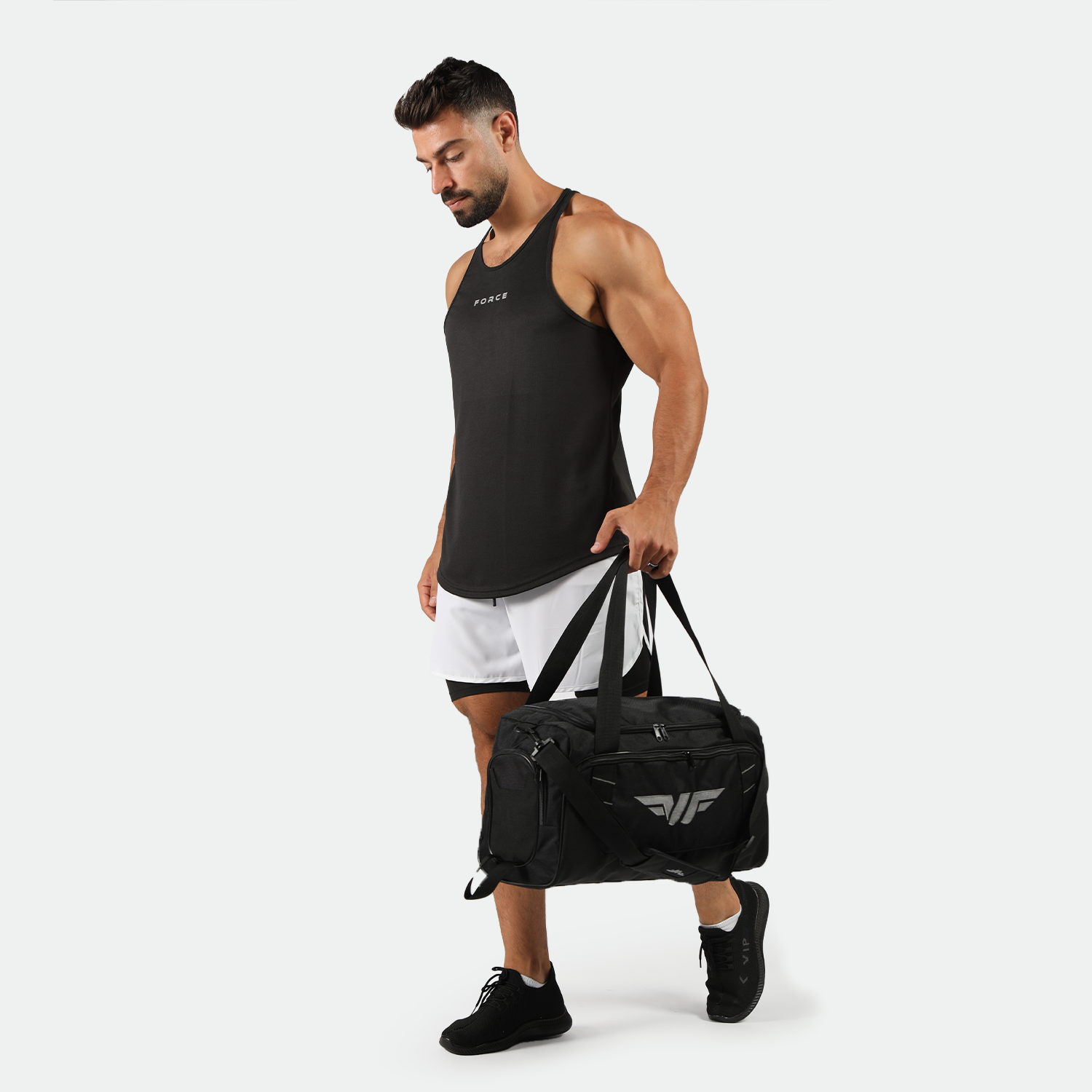 a fit man stand at right and wearing tank black with short 2 in 1 ,plus the bag and shoes 