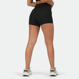 a back view for fit woman  wearing short black with shoes ,plus the background is light grey 