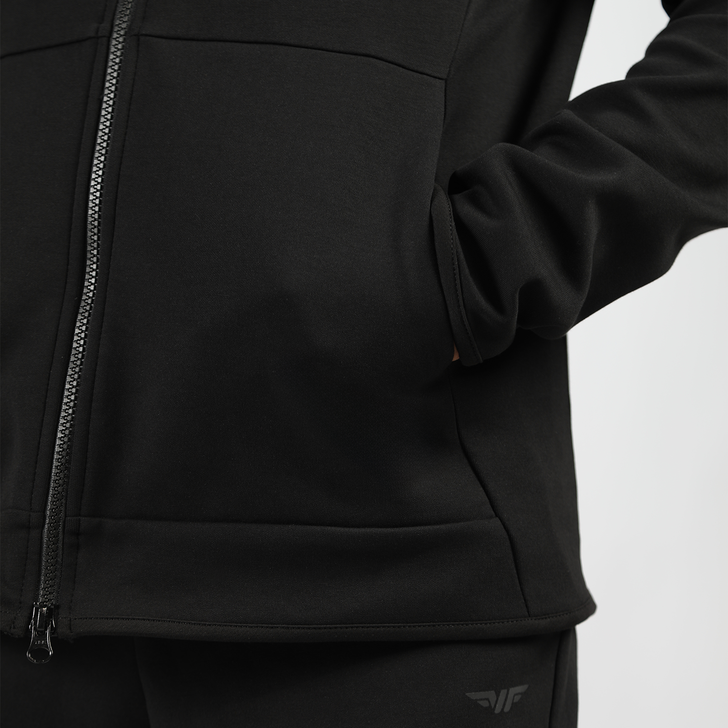 close up view for man wearing  tech zipped hoodie black with pocket ,here hand inside 