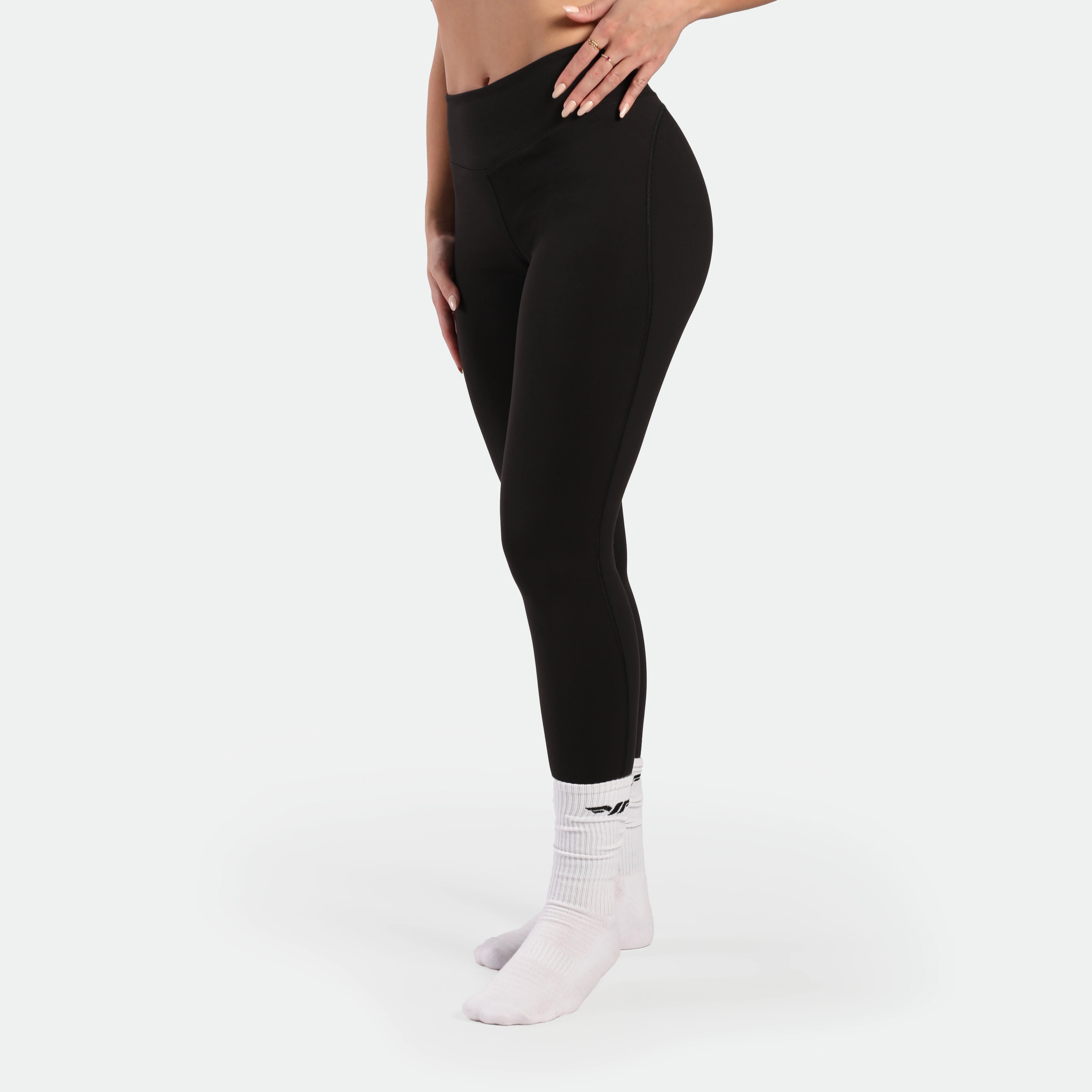 Person wearing black leggings and white socks on a light gray background