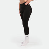 Person wearing black leggings and white socks on a light gray background