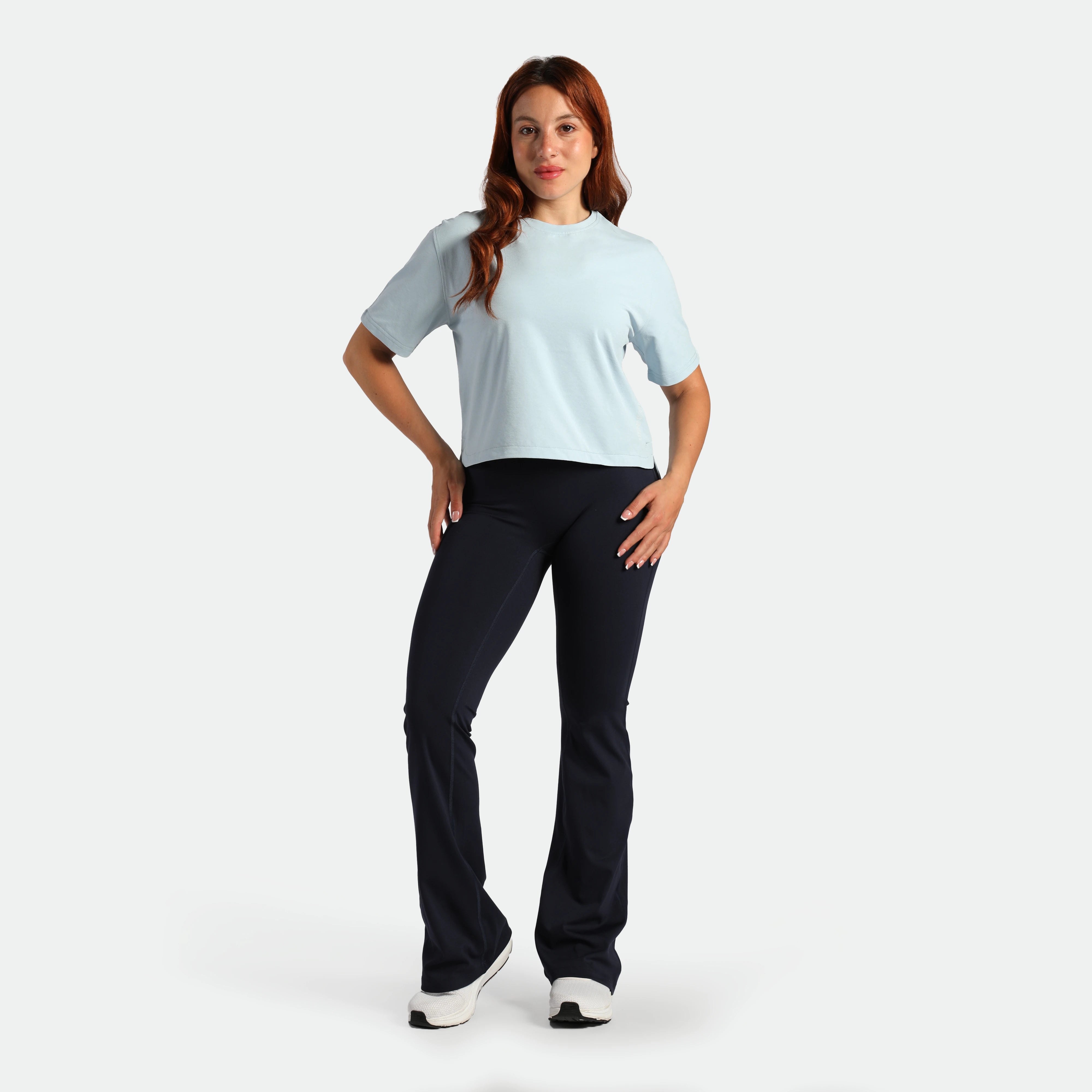 Woman wearing a light blue t-shirt and black pants on a white background