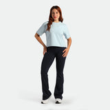 Woman wearing a light blue t-shirt and black pants on a white background
