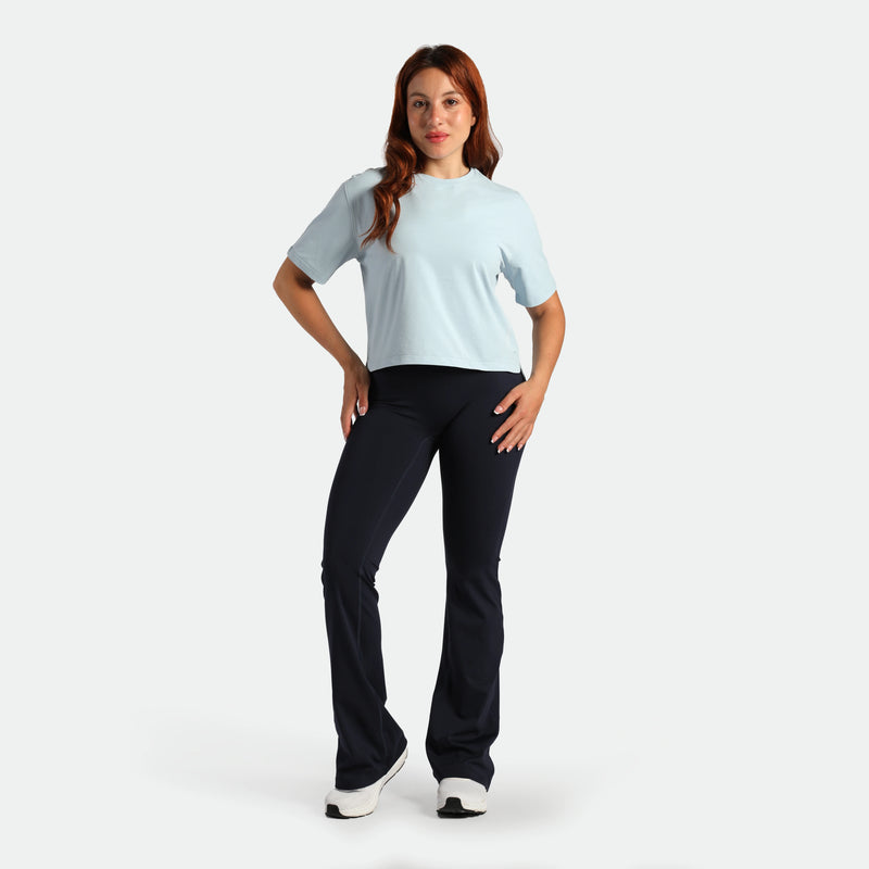 Woman wearing a light blue t-shirt and black pants on a white background