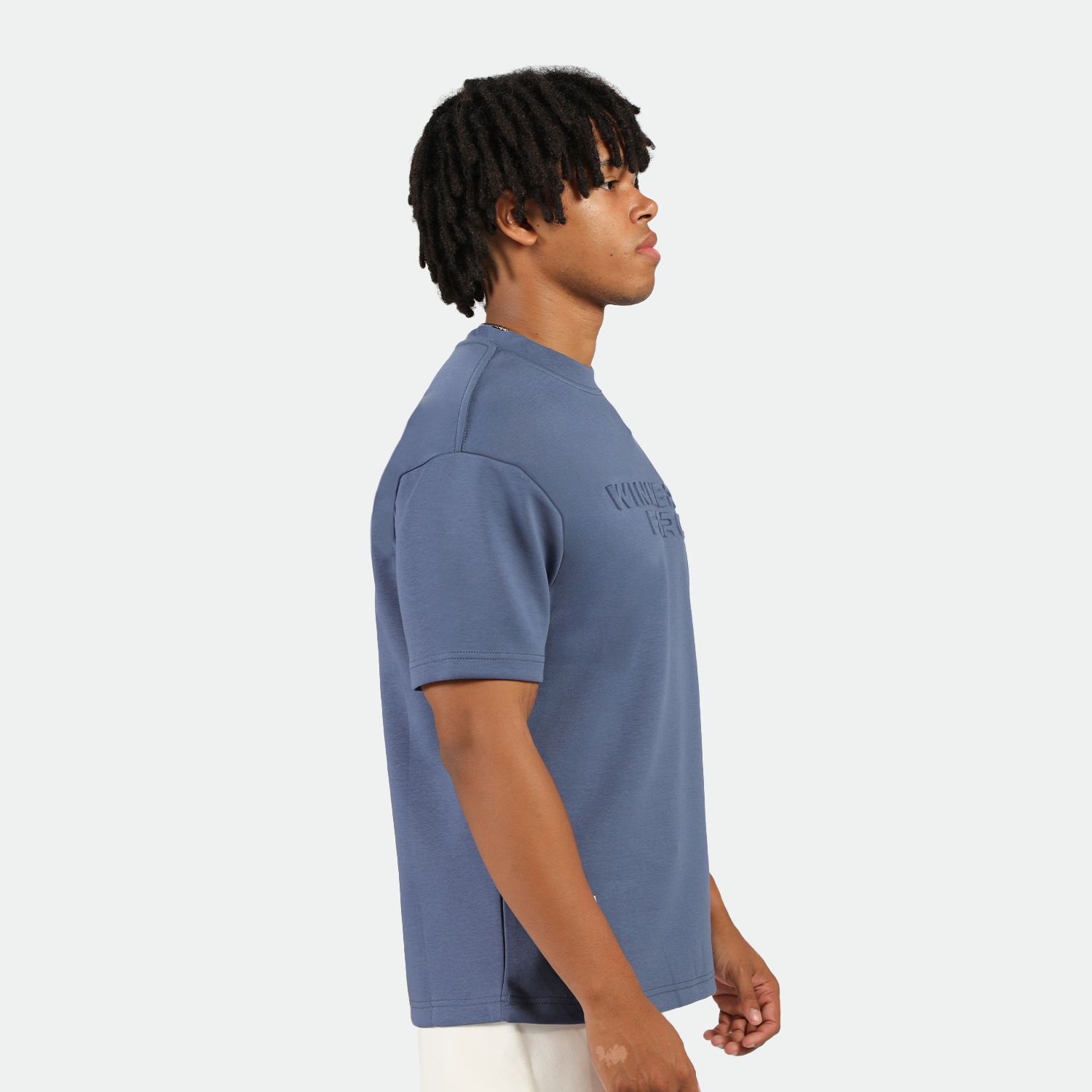 a fit man stand at right and wearing t-shirt indigo blue with short white 