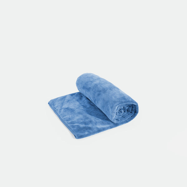 A soft, blue, rolled-up fleece blanket partially unrolled on a plain white background, conveying warmth and coziness, with a plush, inviting texture.