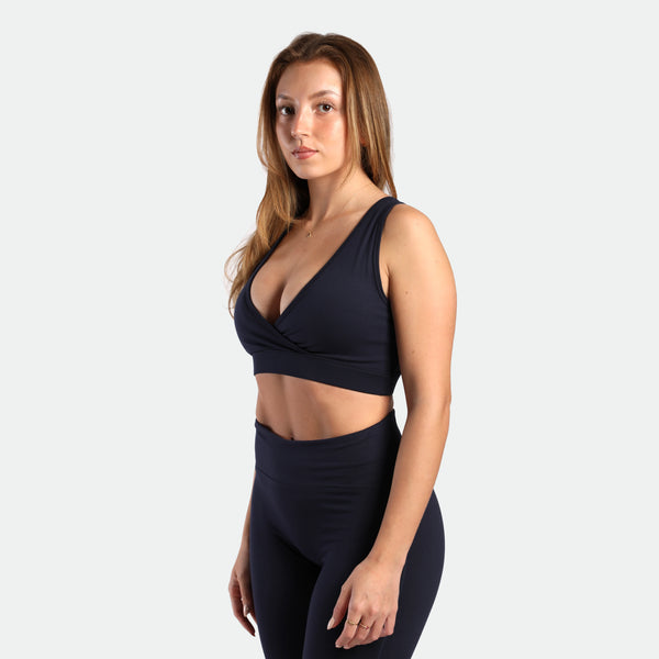 a fit woman stand at right and wearing matching set navy blue ,bra and flared  legging 