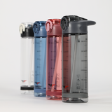 Four water bottles in a row, each with a flip-top lid and measurement markings. Colors are clear, blue, pink, and gray on a white background.